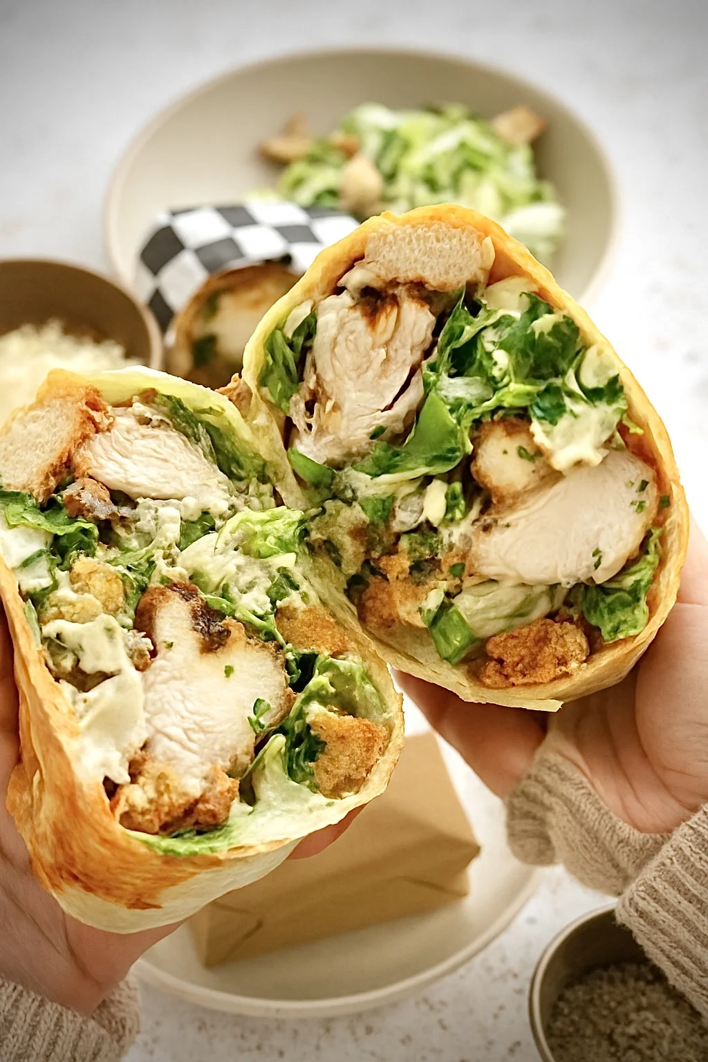 Handheld chicken Caesar wraps with grilled chicken, lettuce, and Caesar dressing in a tortilla