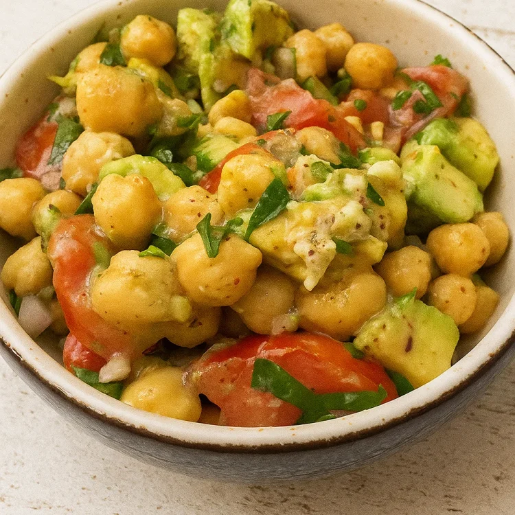 Fresh chickpea and avocado salad served in a bowl with tomatoes and herbs